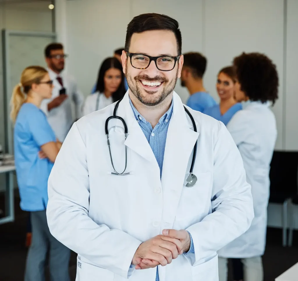 A doctor in a white coat with a hospital team behind him
