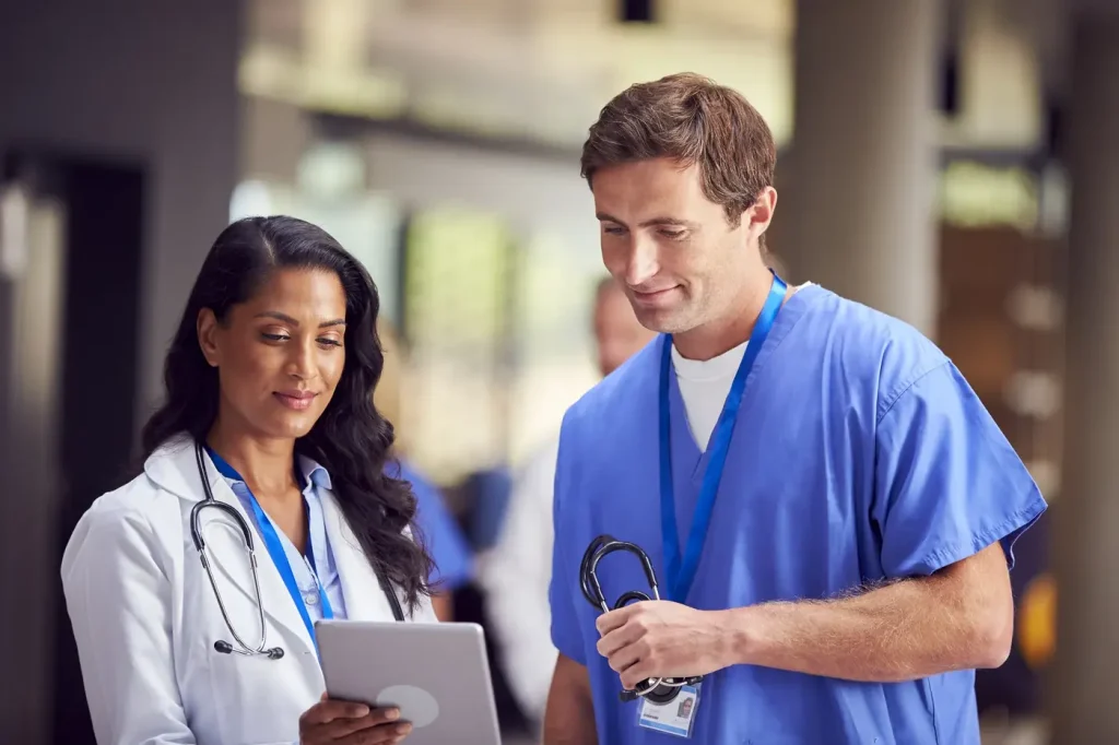 A doctor and a nurse reviewing notes on a tablet