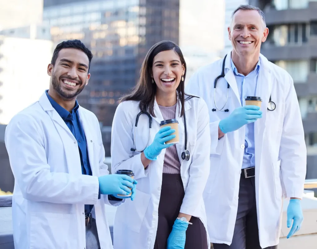 Three doctors in white coats talking together outdoors